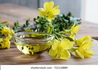 Evening primrose oil in a glass bowl, with fresh evening primrose flowers in the background - Shutterstock ID 721110889
