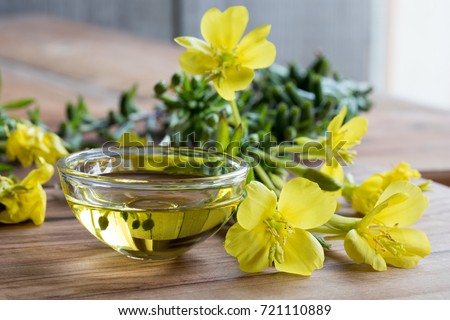 Evening primrose oil in a glass bowl, with fresh evening primrose flowers in the background