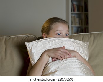 Evening Scene Of Wide-eyed Girl Watching TV From Behind A Cushion