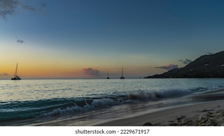 Evening seascape. Turquoise waves are foaming on the shore. Wet sand glistens. Yachts on the horizon. A hill against a background of pinkening sky and clouds. Seychelles. Mahe. Beau Vallon beach - Shutterstock ID 2229671917