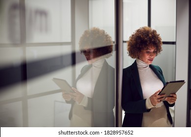 Evening Shot Of Pregnant Businesswoman Standing In Corridor Of Modern Office Using Digital Tablet