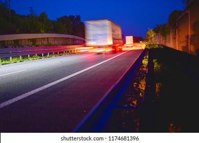 Evening shot of trucks doing transportation and logistics on a highway. Highway traffic - motion blurred truck on a highway-motorway- speedway at dusk.