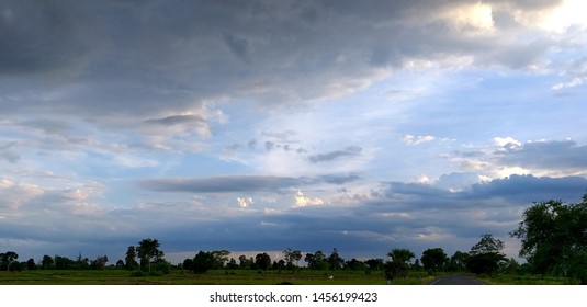 Evening sky atmosphere, which will have large clouds scattered all over, with a wide field and trees line below.