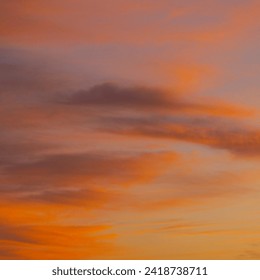 The evening sky is a masterpiece, adorned with the warm hues of a setting sun. Wisps of clouds catch the fading light, transitioning from vibrant oranges and pinks to soothing purples.