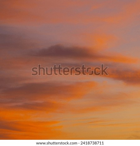 The evening sky is a masterpiece, adorned with the warm hues of a setting sun. Wisps of clouds catch the fading light, transitioning from vibrant oranges and pinks to soothing purples.