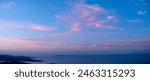 Evening sky with pink clouds over a calm sea and distant mountains, creating a serene and tranquil scene at dusk. huge panorama, ideal for sky replacement, no obstacles.