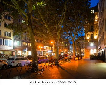 Evening street scene, illuminated downtown with parked cars and bicycles, platan trees, cafes and shops, Frankfurt am Main, Germany
