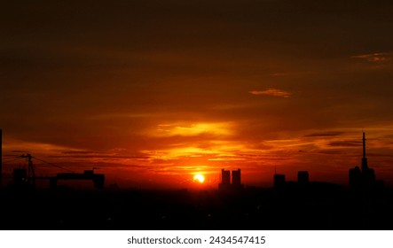 the evening sun is setting in a horizontal line, a beautiful sunset with a golden color shining in the sky, the rays penetrate between the buildings