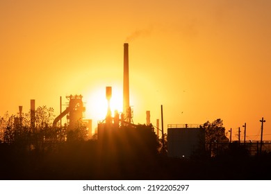 The evening sun shines an industrial smokestack, large factory facility at dusk. - Powered by Shutterstock