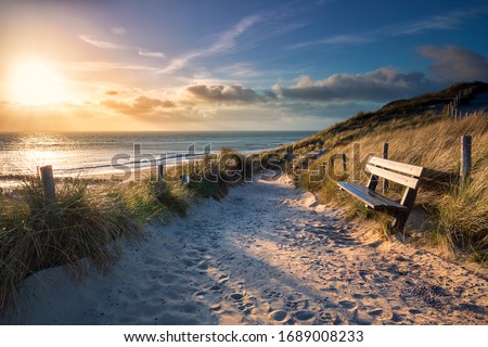 evening sunshine over bench and path to sea beach, Holland