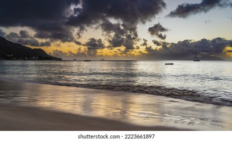 Evening twilight on a tropical beach. Purple clouds in the sky, highlighted in orange. Boats on the water. Reflection on smooth wet sand. Seychelles. Mahe. Beau Vallon - Shutterstock ID 2223661897