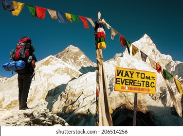 evening view of Everest with tourist and buddhist prayer flags from Kala Patthar, signpost and blue sky - way to Everest Base Camp - Nepal 