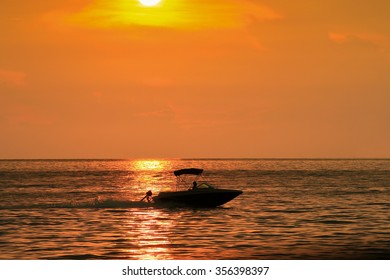 Evening View Of Golden Sunset Photo With A Silhouette Of A Speed Boat Floating On The Sun Reflection