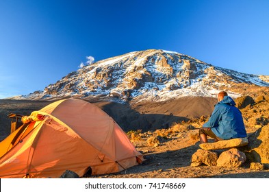 Evening view of Kibo with Uhuru Peak (5895m amsl, highest mountain in Africa) at Mount Kilimanjaro,Kilimanjaro National Park,seen from Karanga Camp at 3995m amsl. Tent and young hiker in foreground.