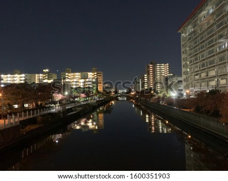 Evening view of river and buildings reflected in the river in Osaka near Sekime station