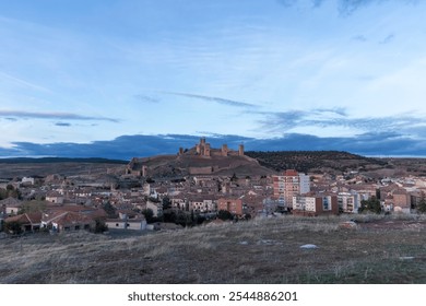 Evening View of a Spanish Town with Historic Castle on Hill Under a Cloudy Sky - Powered by Shutterstock