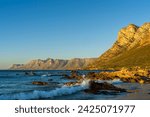 Evening views towards Gordons Bay and the Kogelberg Mountains across False Bay from Rooi-Els beach near Cape Town, Western Cape. South Africa.