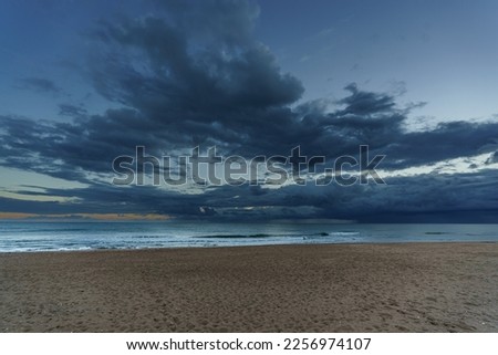 Evening wide view from the beach to the sea with clouds in the background