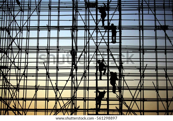 evening, the workers are climbing the\
silhouette of scaffolding in the high altitude, horizontal and\
vertical scaffolding formed a myriad of grid, industrial and modern\
urban construction\
background.