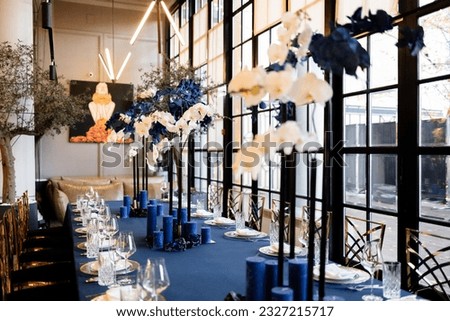 Event decor, beautiful restaurant interior, table setting, gold decor, blue candles on a blue table, light filling, atmospheric evening, 24mm horizontal photo.
