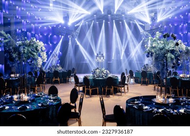 Event decor with chic table setting with blue tablecloths and flowers. Scene in the background. Light filling.