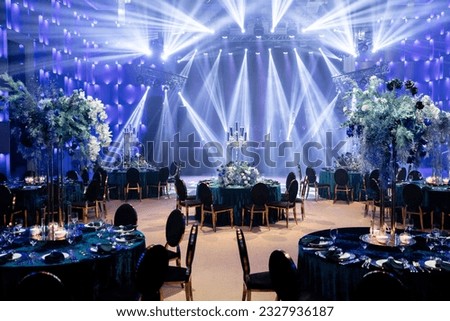 Event decor with chic table setting with blue tablecloths and flowers. Scene in the background. Light filling.