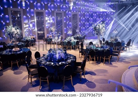 Event decor with chic table setting with blue tablecloths and flowers. Scene in the background. Light filling.