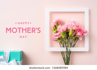 Event Design Concept - Top View Of A Bunch Of Pink Carnation With White Photo Frame, Gift Box And Greeting Word On Pink Background For Mothers Day Event With Copy Space For Mock Up