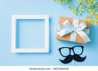 Event Design Concept - Top View Of Fathers Day Layout With White White Square Frame, Ribbon Kraft Gift Box, Yellow Flower And Gentleman Silhouette On Blue Background, Copy Space For Mock Up