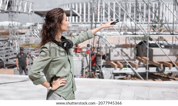 Event manager portrait. Installation of stage\
equipment and preparing for a live concert open air. Summer music\
city festival. Woman works on the\
stage.