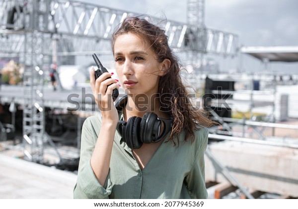 Event manager portrait. Installation of stage\
equipment and preparing for a live concert open air. Summer music\
city festival. Woman works on the\
stage.