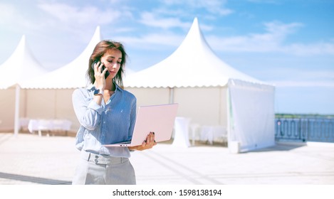 Event Manager Portrait. Preparation For Public Exhibition And Global Business Expo. Young Serious Woman Stand And Work With Her Laptop Near The Mobile Tents. Installation Of Exhibition Pavilions. 