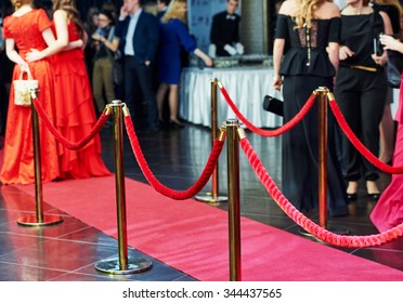 Event Party. Red Carpet Entrance With Golden Stanchions And Ropes. Guests In The Background 