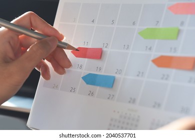 Event Planner Timetable Agenda Plan On Organize Schedule Event. Business Woman Checking Planner On Mobile Phone And Taking Note On Calendar Desk On Office Table. Calendar Event Plan, Work Planning