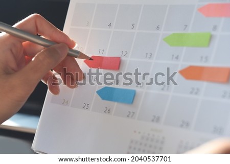 Event planner timetable agenda plan on organize schedule event. Business woman checking planner on mobile phone and taking note on calendar desk on office table. Calendar event plan, work planning