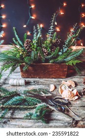 Evergreen Christmas Centerpiece In The Making On A Wooden Background With Lights 