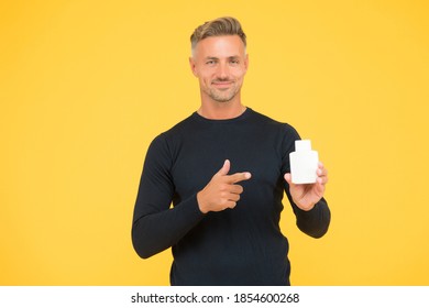 Every Man Needs Some Care. Handsome Man Point Finger At Bottle Yellow Background. Skin Care Cosmetics. Skincare Beauty Product. Barbershop. Mens Grooming. Hair Salon. Haircare.