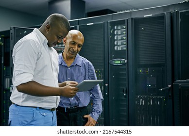For every IT problem, they have a solution. Shot of two IT technicians using a digital tablet while working in a data center.