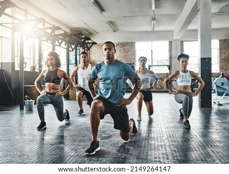 Every step taken towards fitness pays off. Shot of a group of young people doing lunges together during their workout in a gym.