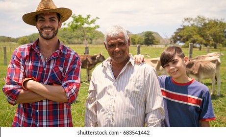 Everyday Life For Farmers With Cows In The Countryside. Peasants Work In Latin America With Livestock In Family Country Ranch. Portrait Of Happy Grandfather, Dad And Child Smiling.