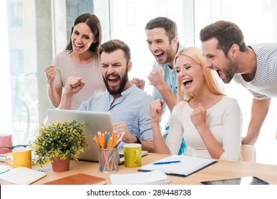 Everyday winners. Group of happy business people in smart casual wear looking at the laptop and gesturing 