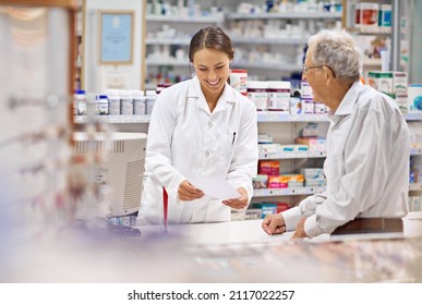 Everyone Of My Clients Are Special. Shot Of A Young Pharmacist Helping An Elderly Customer At The Prescription Counter.