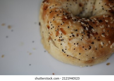 Everything Bagel On White Plate Scattered Seasoning Top Right Corner Close Up