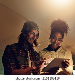 Everything Is Coming Together Now. Shot Of Two Coworker Discussing Something On A Digital Tablet While Working Night Shift At The Office.