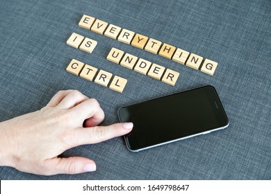 Everything is under control, flat lay message from wooden blocks and hand on mobile phone
