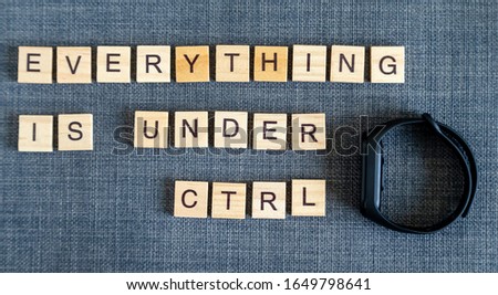 Everything is under control, flat lay message from wooden blocks and sport watch