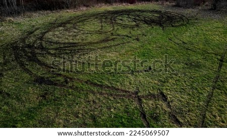 evidence of damage to agricultural land by car skidding. the police use a drone to document the damage after youths rampage in cars on the meadow. ruts into circles from spinning tires, landscape