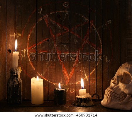 Evil candles and scary skull against wooden background with bloody pentagram.  Halloween concept, black magic ritual or spell with occult and esoteric symbols, divination rite 