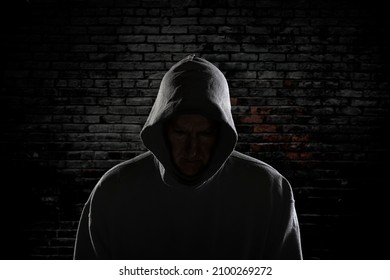 An Evil Looking Man With A Hidden Face And Wearing A Hoodie Stands Intimidatingly Against An Ally Wall Stalking His Next Victim.

