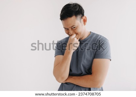 Evil looks of asian man in blue t-shirt smile and smirk stand isolated on white.